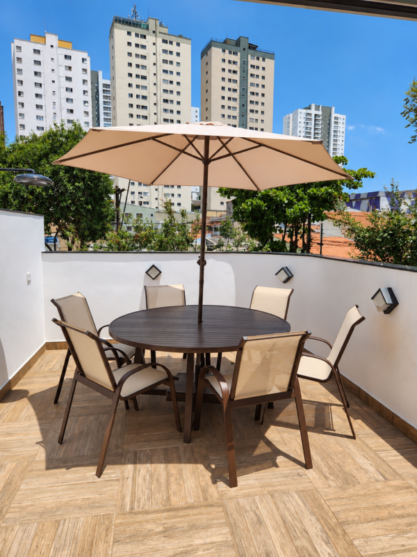 Conjunto de mesa Classic alumínio com mesa redonda marrom e seis cadeiras de tela sling bege em um terraço