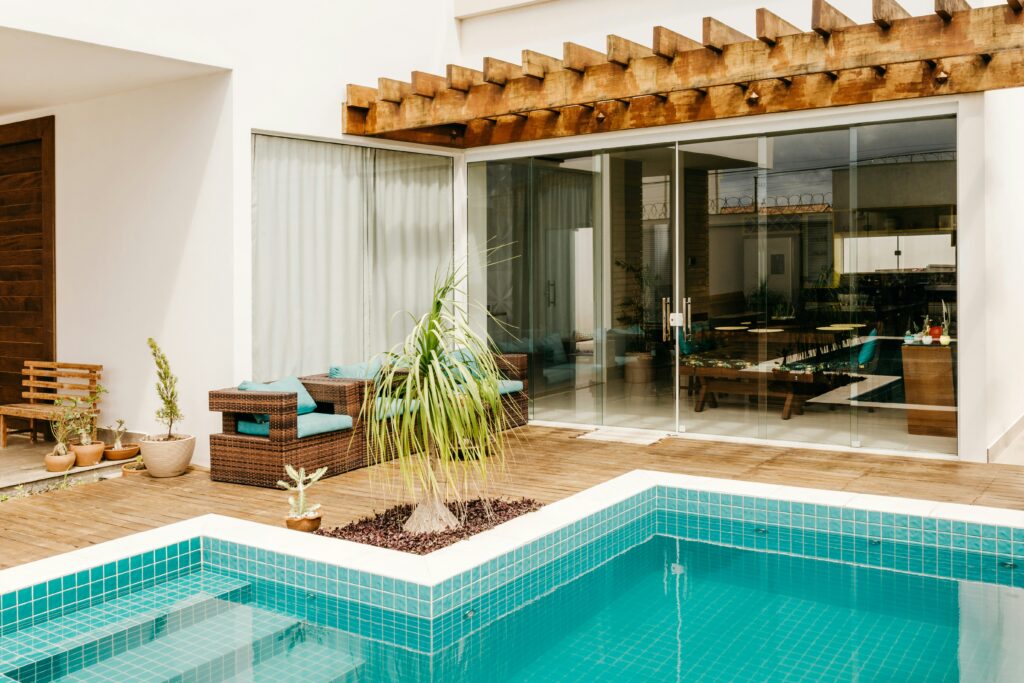 Piscina residencial com deck de madeira, pergolado e área de descanso