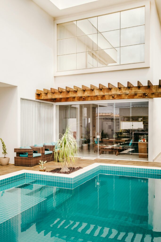 Área de lazer com piscina, deck de madeira e pergolado em residência
